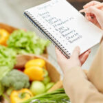 Hand of a lady marking her budgets using budgeting hacks